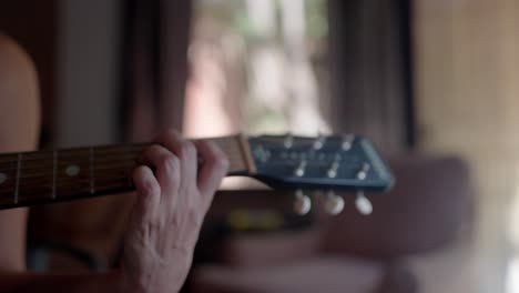 close up view of a girl hand playing an acoustic guitar in a home studio.