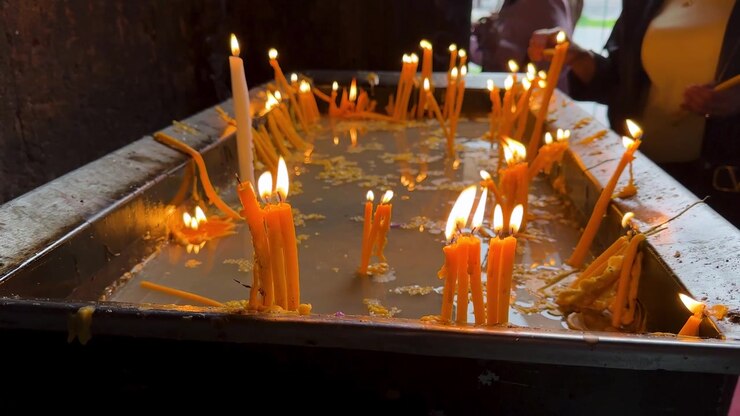 people worship pray the meditation spiritual devotion in dark quiet church sanctuary with interior wooden table and wax yellow color candle flame glow peaceful candlelit dim room in Yerevan Armenia