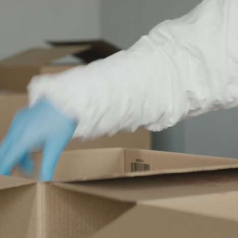 a person in protective gloves packs food into a cardboard box