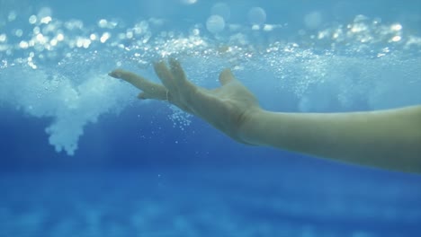 mano femenina haciendo gestos bajo el agua