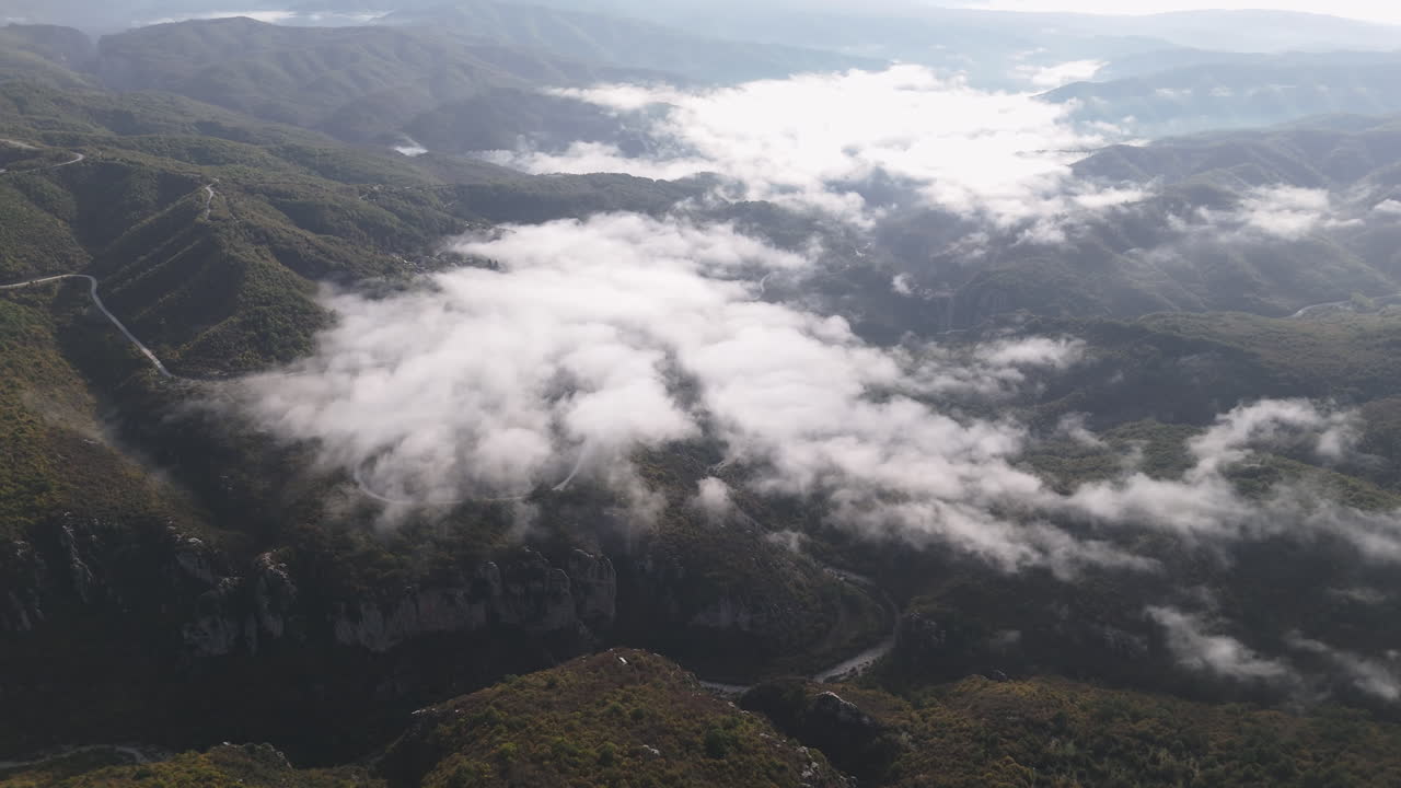Aerial establishing view of Vikos Gorge with misty, dramatic cliffs and rugged landscapes in central Zagori, roads winding through mountains