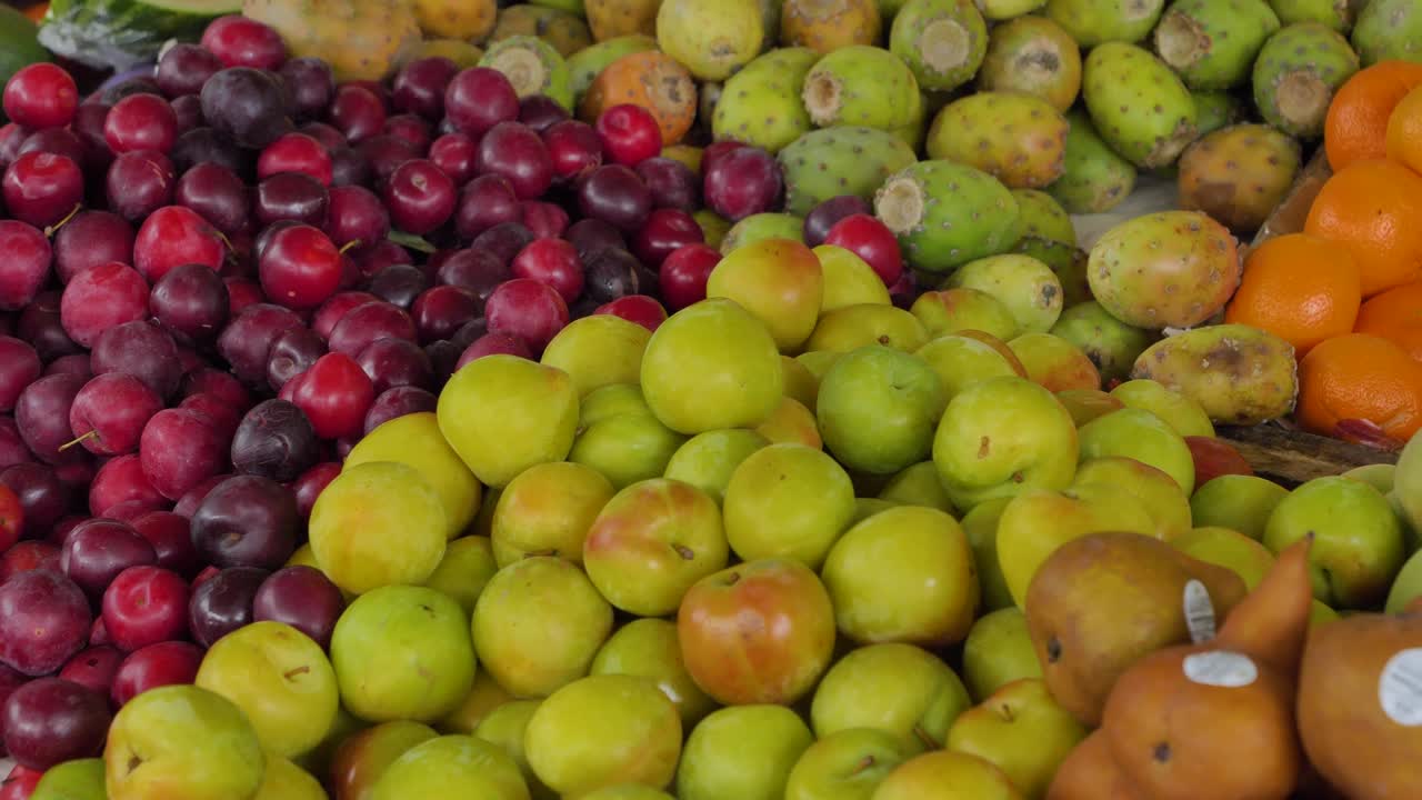 Pannende close-up van gemengd fruit waaronder pruimen en citrusvruchten op een marktkraam