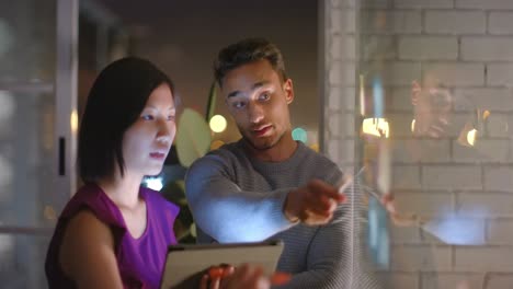 Colegas-Masculinos-Y-Femeninos-Enfocados-En-La-Lluvia-De-Ideas-Y-El-Uso-De-Tabletas-Por-La-Noche-En-La-Oficina