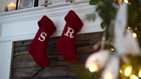 christmas stocking hanging above the fireplace for santa claus to fill - sliding view with the decorated tree in the foreground