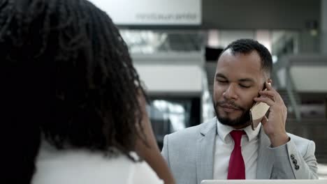 Focused-young-businessman-talking-on-smartphone-and-gesturing