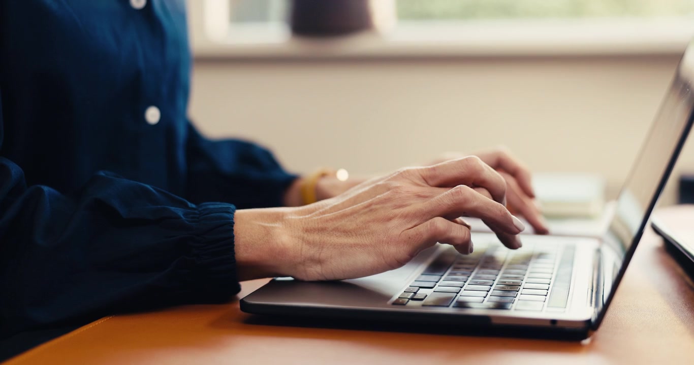 Person Typing on Laptop Keyboard in Office Setting