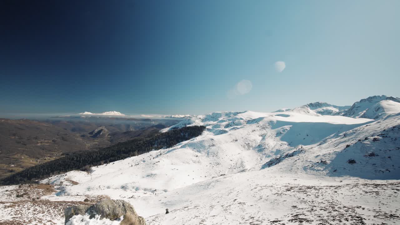 Sunset over mountain silhouettes, casting warm hues across the sky, a serene evening scene.