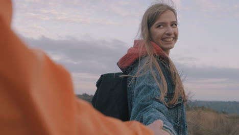 joven excursionista que lleva a su pareja de la mano en la naturaleza