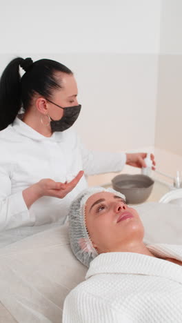 cosmetologist cleanses young woman face with foam cleanser before facial therapy in beauty clinic