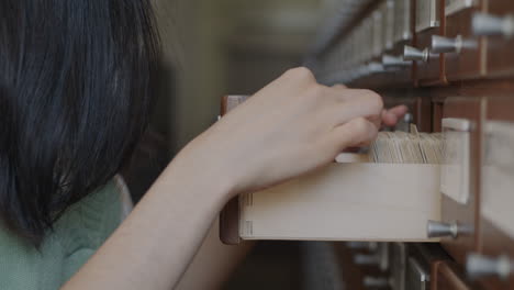 woman searching through a card catalog drawer