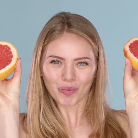 slow motion video of a beautiful happy smiling young blonde woman with grapefruit halfs