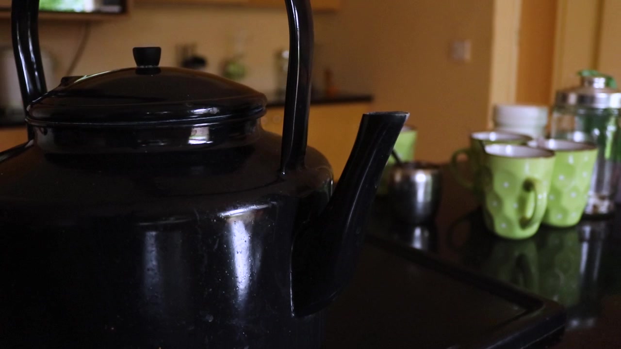 Close up shot of a person pouring out water into the glass cups from a teapot at breakfast on the table at Harare, Zimbabwe.