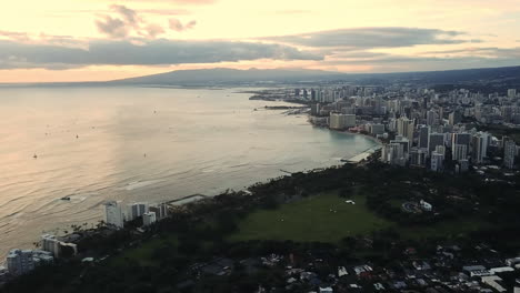 Rising-aerial-view-of-Waikiki-Beach,-Honolulu-during-sunset-golden-hour