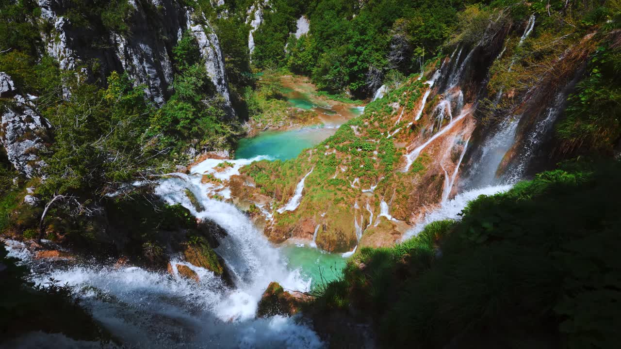 Waterfalls cascading down cliffs with greenery and rainbow at Plitvice Lakes National Park, Croatia