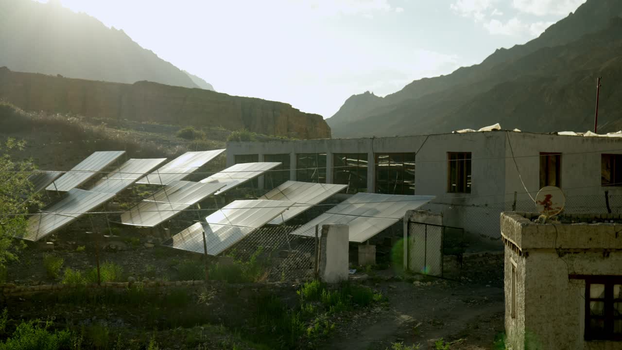 Solcellepark ved et homestay i den fjerntliggende Markha-dal, Leh, Ladakh, der leverer strøm til en landsby uden vejadgang. Aftensolen reflekteres lavt over solpanelerne i et fantastisk himalayansk landskab