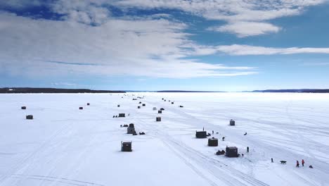 an aerial view of ice fishing huts on a frozen lake on a beautiful winter day in northern ontario