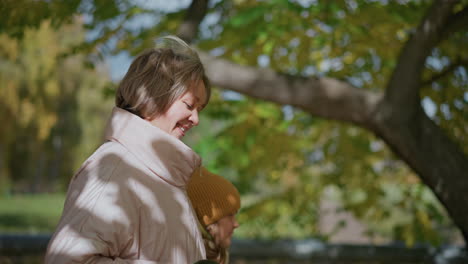 young mom strolls side by side with son through vibrant autumn park, both glancing toward distant scene as mom holds dog leash loosely, golden foliage overhead and sunlit pathway