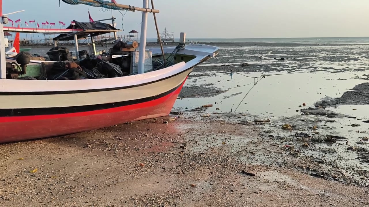 Barca da pesca tradizionale arenata su una riva fangosa con la bassa marea