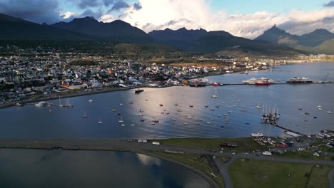 Patagonian-Landscape-in-Ushuaia-City-Argentina,-Water-Bay-Port-with-Mountain-Range-Shining-at-the-Dreamy-Horizon,-Aerial-Drone-View