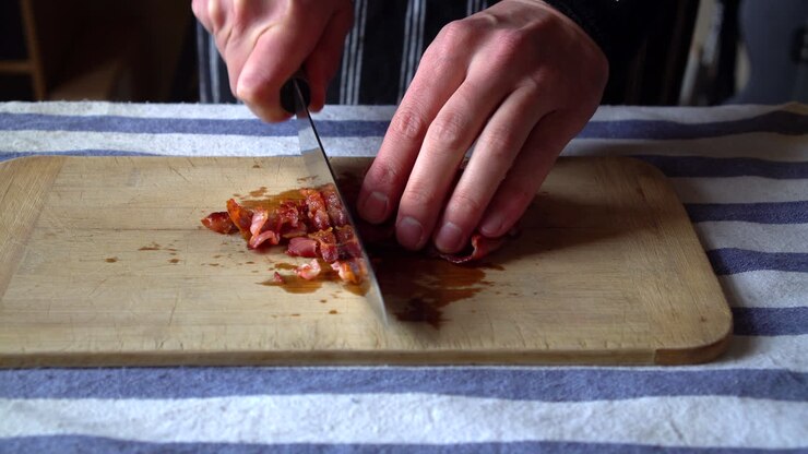 Front View of a Man Chef chopping crispy bacon for breakfast