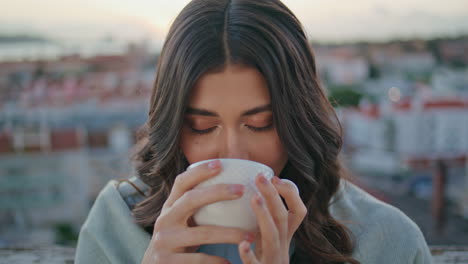 mujer tierna bebiendo espresso vista del balcón al atardecer retrato de la ciudad. chica relajada