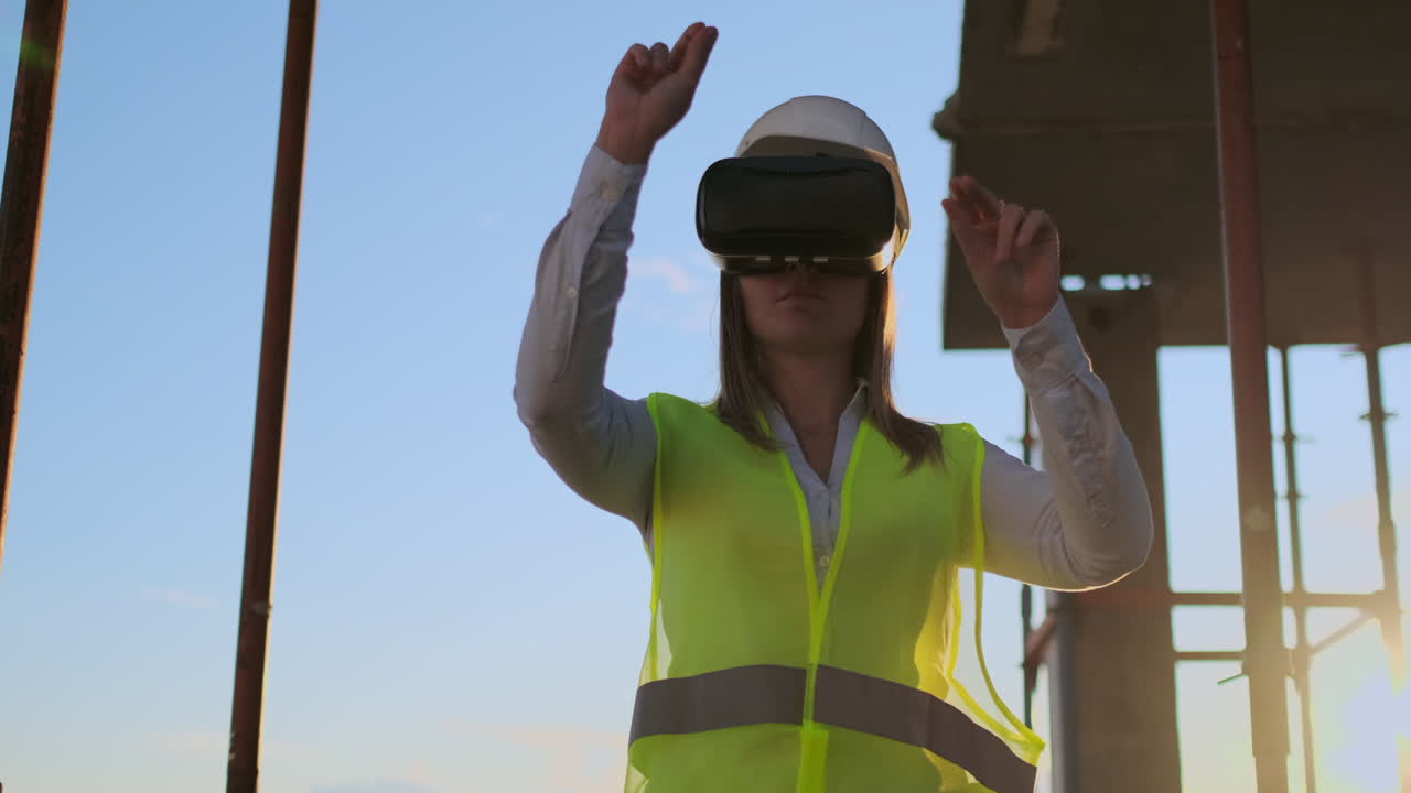inspector mujer en gafas vr y casco comprueba el progreso de la construcción de un rascacielos moviendo sus manos al atardecer visualizando el plan del edificio