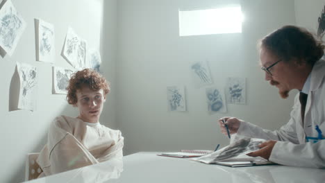 psychiatrist showing abstract drawing to restrained patient on clinical session