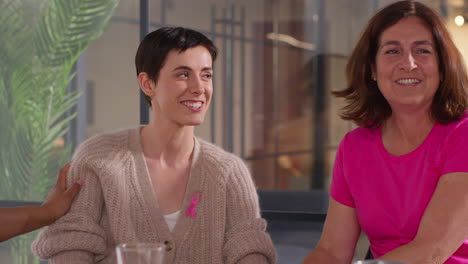 group of women wearing pink breast cancer awareness ribbons meeting and talking at therapy support group for cancer treatment patients 5