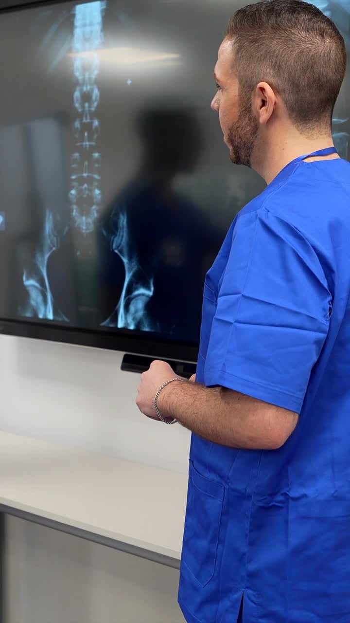 Professionisti medici che discutono una radiografia su un grande schermo.
