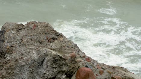 Big-stormy-waves-breaking-against-abandoned-seaside-fortification-building-ruins-at-Karosta-Northern-Forts-in-Liepaja,-Baltic-sea-coastline,-wave-splash,-overcast-day,-medium-angle-closeup-shot