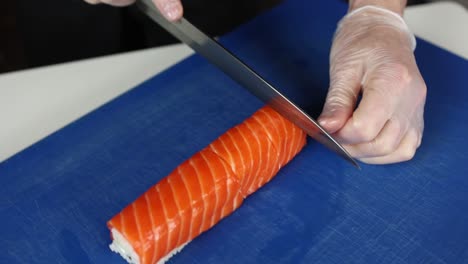 el chef está preparando un rollo de sushi de salmón.