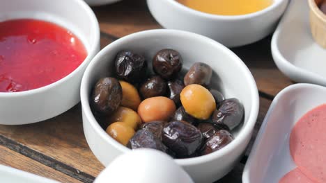 un primer plano de una bandeja de desayuno con aceitunas, salsa roja y salami