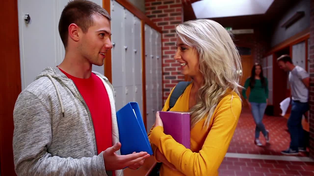 dos estudiantes lindos coqueteando en el pasillo