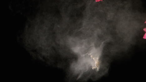 un globo rosado perforado con dardos en cámara lenta