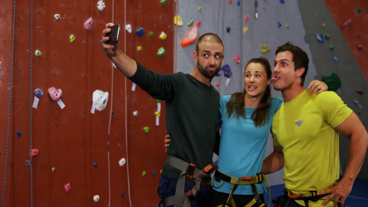 hombres y mujeres tomando una selfie en el gimnasio de bouldering 4k
