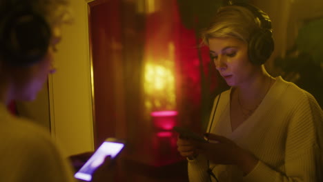 two friends using phones in a room