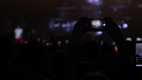 fan asistiendo a un concierto por la noche y filmando música en vivo filmando en un smartphone