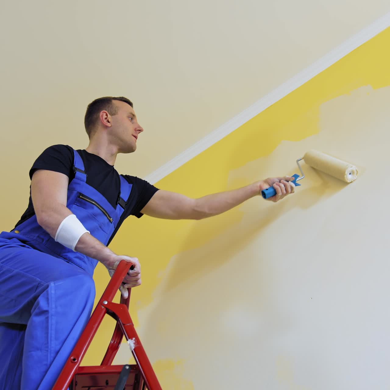 Apartment redecoration and home construction. Caucasian man paints the wall with roller