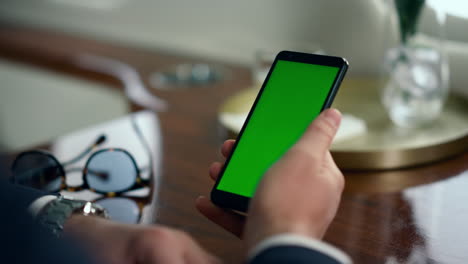 Geschäftsmann-Wischt-Mit-Der-Hand-über-Den-Grünen-Smartphone-Bildschirm,-Nahaufnahme.-Mann-Benutzt-Mockup-Gerät
