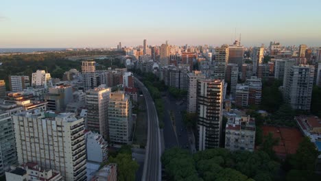 Dolly-in-flying-over-train-rails-near-park-in-Belgrano-neighborhood-whith-river-in-background,-Buenos-Aires,-Argentina