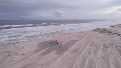 Flying-Over-Flat-Dense-Wet-Sand-On-Stockton-Beach-In-New-South-Wales,-Australia