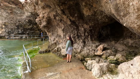 woman walking into sandstone water cave