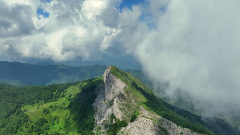 flying trough white fluffy clouds above green mountain peaks