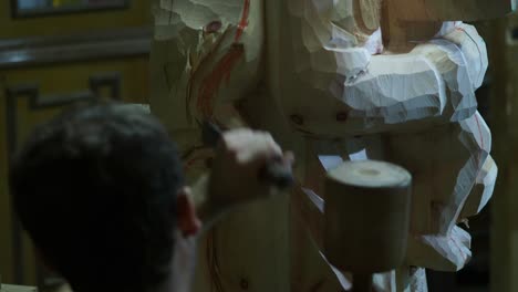 skilled italian adult fit artisan carefully carving wooden madonna sculpture, meticulously shaping intricate details with traditional manual tool in refined slow-motion woodworking process