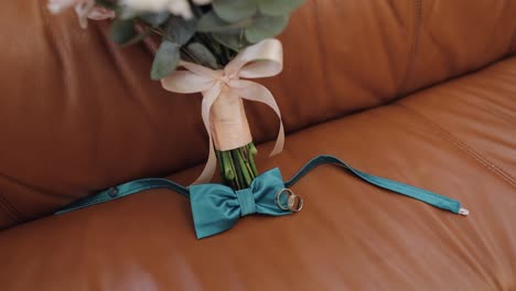 Beautiful-wedding-bouquets-lie-with-wedding-rings-and-grooms-bow-tie-on-sofa