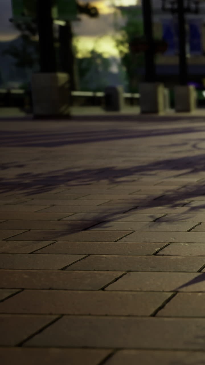 Shadows cast on pavement during evening walk in urban area with lights