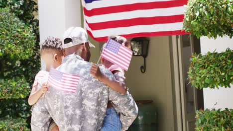 feliz soldado afroamericano regresando a casa, sosteniendo a su hijo e hija con banderas, cámara lenta