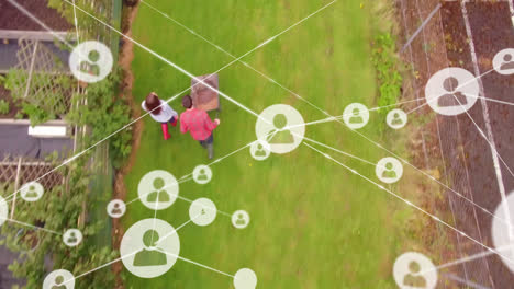 Network of profile icons against aerial view of caucasian couple with garden cart in the garden
