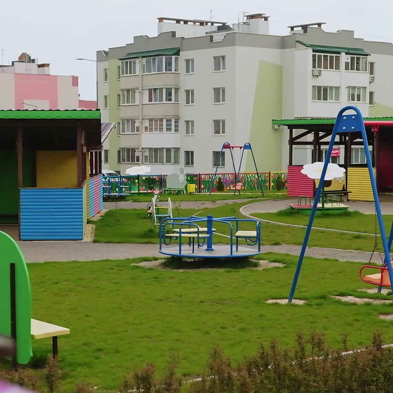 Lovely colorful cozy playground territory with green grass. New apartment buildings at backdrop