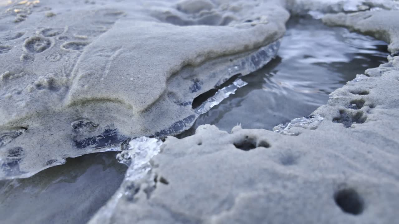 The edges of a sandbank in the ice, through which water flows during the winter, create a unique landscape as the current shapes the ice and sand.